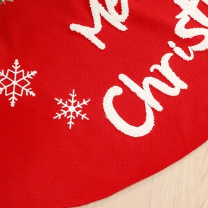 Red knitted Christmas tree skirt featuring white snowflake embroidery on wooden floor