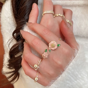 Gros plan d'un ensemble de bagues fleuries avec nacre et zircons sur une main de mannequin