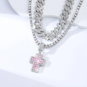 Detail of silver Cuban link and tennis chain set with pink stone cross pendant