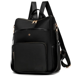 Front detail of black nylon backpack with gold metal zippers and leather texture handles