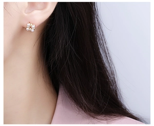 Close-up of elegant flower pearl earrings with gold rhinestones worn on the earlobe