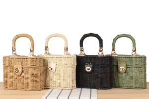 Row of woven straw box handbags in light brown, beige, black, and olive green on wood