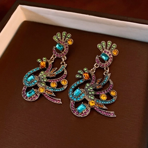 Macro detail of Bohemian colorful rhinestone earrings with vintage gold peacock wing design