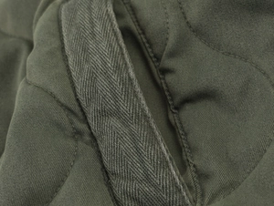 Detailed close-up of olive green twill fabric with herringbone tape and precision stitching