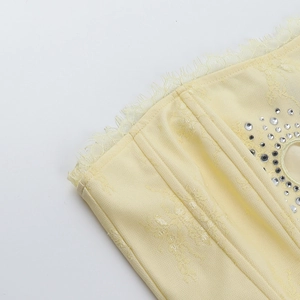 Gros plan du haut en dentelle jaune orné de motifs en strass et de finitions raffinées