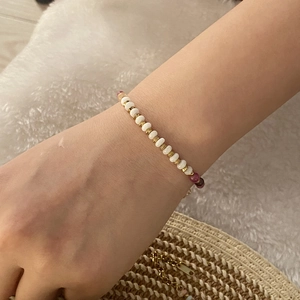 Detailed shot of handmade beaded bracelet with white and purple stones on a soft white background