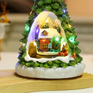 Macro detail of glowing Christmas tree miniature with music box and colorful LED house
