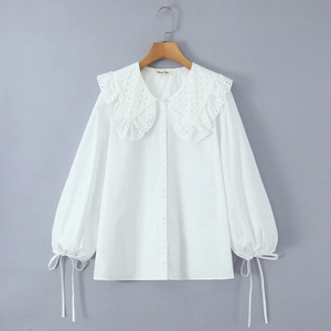 Details einer weißen Bluse mit Spitzenkragen und Laternenärmeln mit Schleifenbündchen