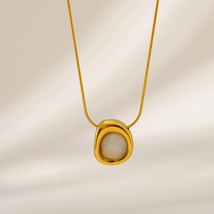 Close-up of golden irregular pendant with white round stone on a sleek snake chain