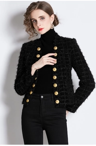 Detail of black tweed jacket featuring golden embossed buttons and textured woven fabric