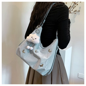 Macro detail of metallic blue pleated shoulder bag with butterfly charm and cloud pendant