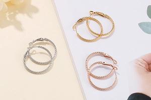 Detail of round hoop earrings in gold, silver, and rose gold with spiral metal texture