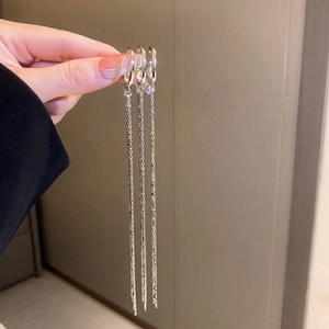 Detail showing long silver tassel chain earrings held in hand to display length and drape