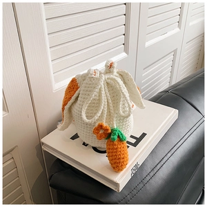 Detail of handmade crochet bucket bag with orange rabbit ears on a fashion coffee table book