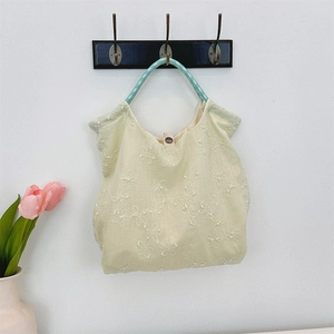 Detail view of floral embroidery on beige canvas tote with woven teal handles
