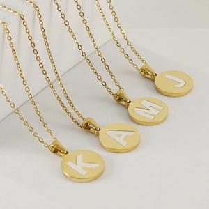 Detail of four 18K gold plated necklaces with white shell alphabet pendants K, A, M, J