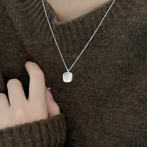 Close-up of minimalist 925 sterling silver S-letter pendant necklace on a dark sweater