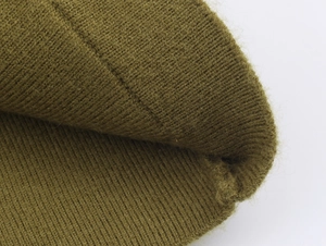 Macro del tessuto a maglia verde oliva che mostra la trama fine e le fibre di lana
