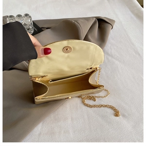 Detail of small gold evening bag showing magnetic closure, interior space and chain strap