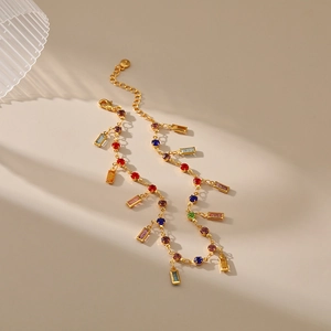 Detail of gold ankle bracelets featuring colorful round and rectangular crystal pendants