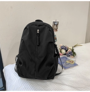 Close-up of black minimalist backpack with woven zipper pulls in a lifestyle setting