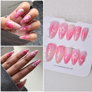Detail of almond press-on nails featuring 3D flowers, golden beads and butterfly art