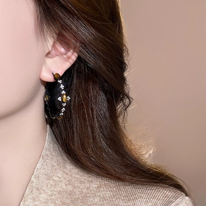 Close-up of vintage C-shape hoop earring with tiger eye stone and crystals on a model