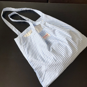 Dettaglio della borsa tote in cotone a righe bianche e blu con etichetta rossa Bébé