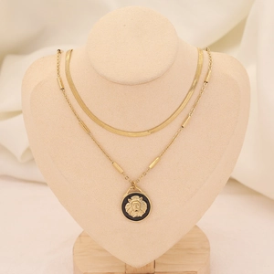 Détail d'un collier multicouche doré avec chaîne serpent et pendentif tête de lion noir