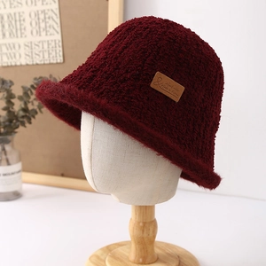 Detail of burgundy plush bucket hat showing faux fur texture and leather side label