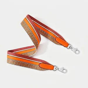 Detailed view of the wide woven strap with orange leather ends and silver metal clips