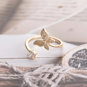 Golden butterfly open ring with micro-set cubic zirconia on an artistic vintage book background