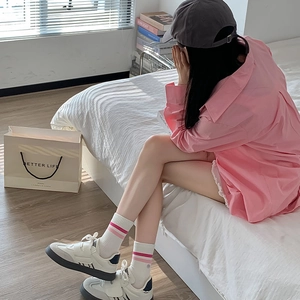Detail of white mid-calf socks with pink stripes paired with casual sneakers and outfit