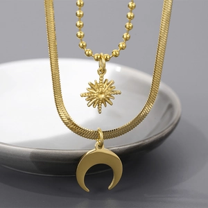 Double-layered gold necklace with moon and sun pendants on a snake and bead chain