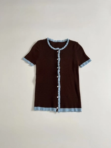 Detail of slim-fit knit top featuring contrast ruffle trim and vertical ribbed texture
