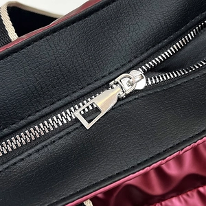 Detail of silver metal zipper on black textured PU leather and burgundy quilted fabric