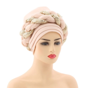 Detail view of pink turban hat with golden sequin braids on a white mannequin head