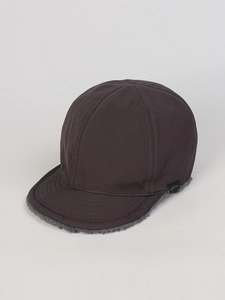 Dettaglio del cappellino invernale marrone scuro con fodera in sherpa grigio e marchio