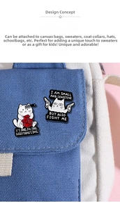 Detail of two white enamel cat pins on a blue bag, featuring a D20 die and slogans