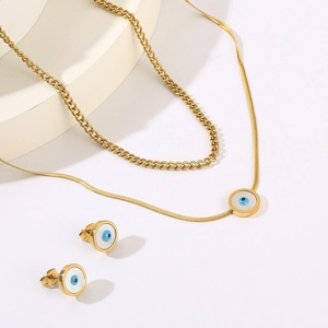 Detail of gold evil eye jewelry set featuring layered snake chain and stud earrings
