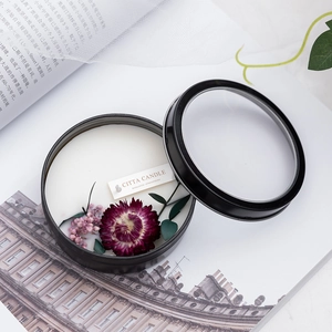 Scented soy candle in black metal tin with decorative dried flowers and glass lid