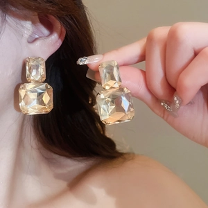 Macro view of geometric champagne crystal square earrings set in polished gold finish