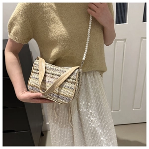 Gros plan sur un sac à bandoulière en paille tissée avec une sangle en perles blanches