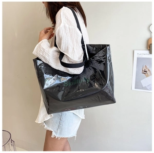 Close-up of a large black glossy tote bag with green Skillfully lettering and woven straps