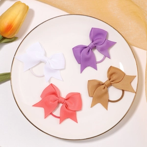 Set of four grosgrain ribbon ponytail holders in white, purple, pink and gold on a white plate