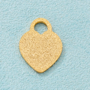 Golden frosted heart pendant with glitter texture on a light blue textured background