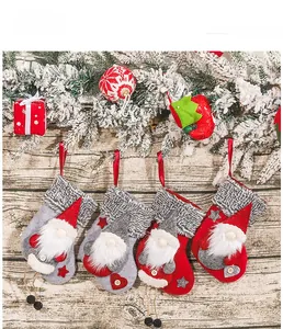 Close-up of four handmade Christmas gnome stockings hanging from snowy pine branches