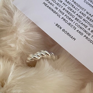 Detailed macro view of the twisted croissant ring texture on a soft white fur backdrop