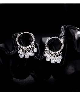 Macro shot of S925 silver hoop earrings with dangling teardrop cubic zirconia on dark silk