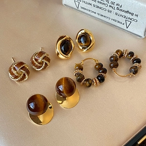 Detailed set of 5 pairs vintage tiger eye beaded earrings on beige leather background